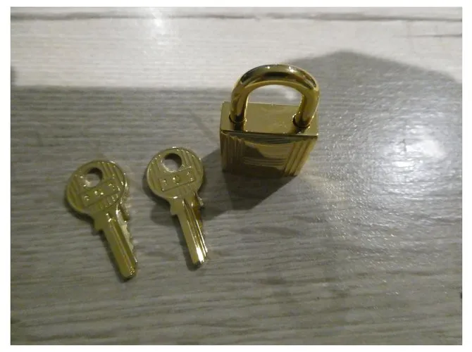 Candado de acero dorado Hermès con 2 llaves 